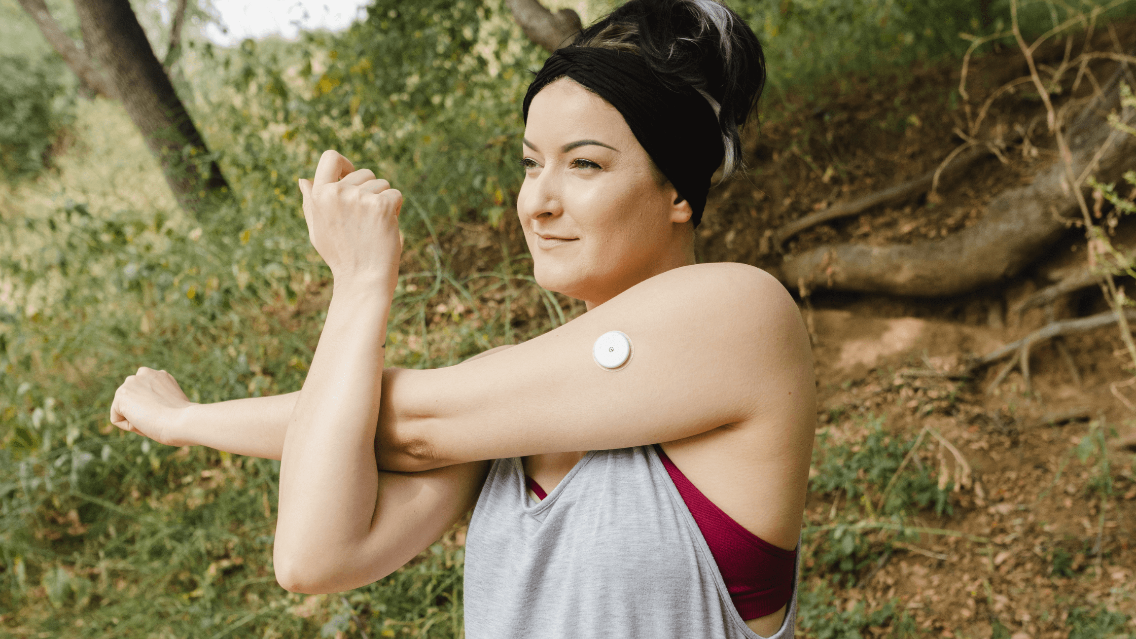 Woman with a continuous glucose monitor (CGM) stretching outdoors, representing active lifestyle and diabetes management for eye health.