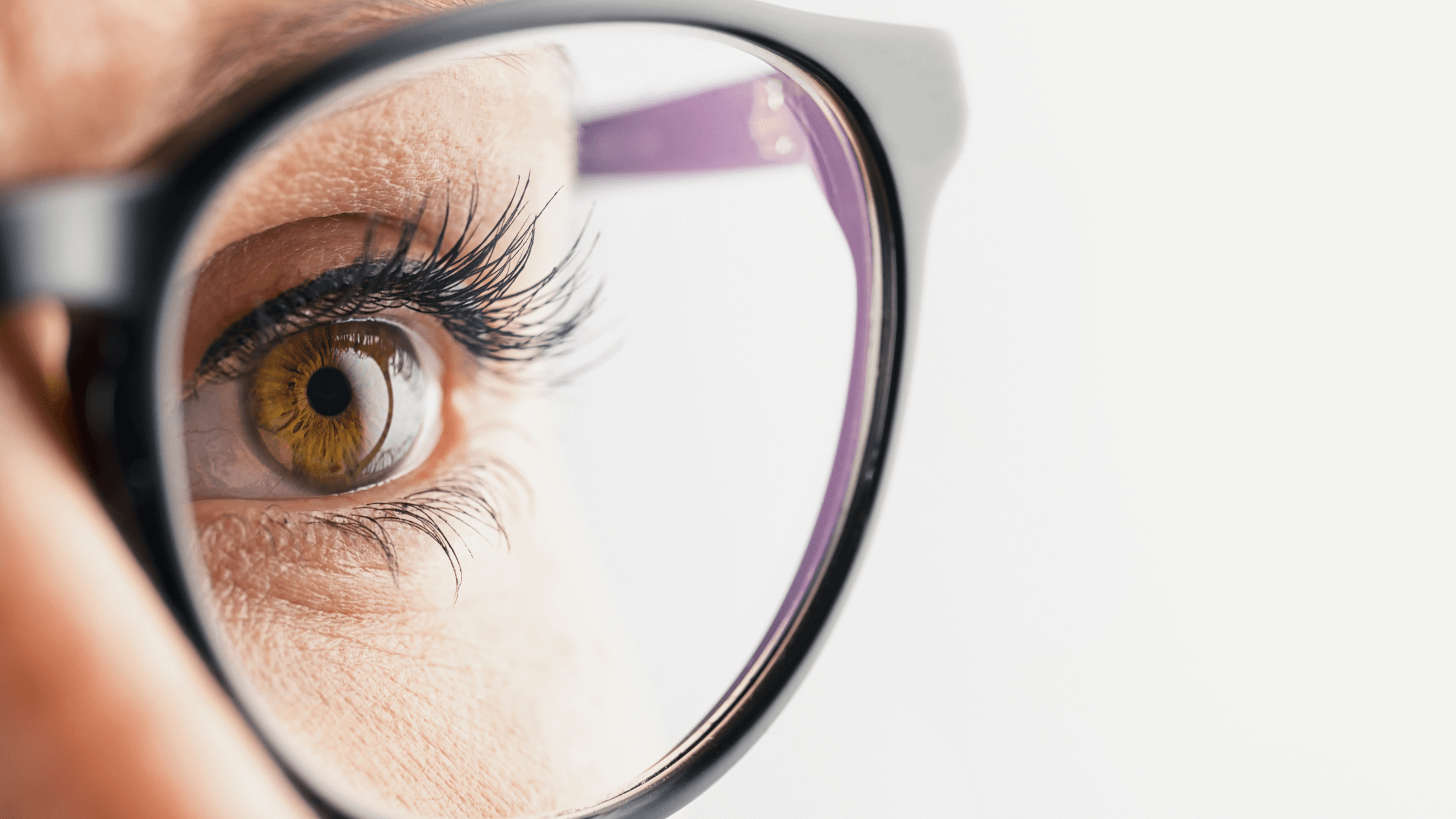 A close-up of a person's eye seen through a pair of glasses, representing the initial eye exam during a LASIK consultation.