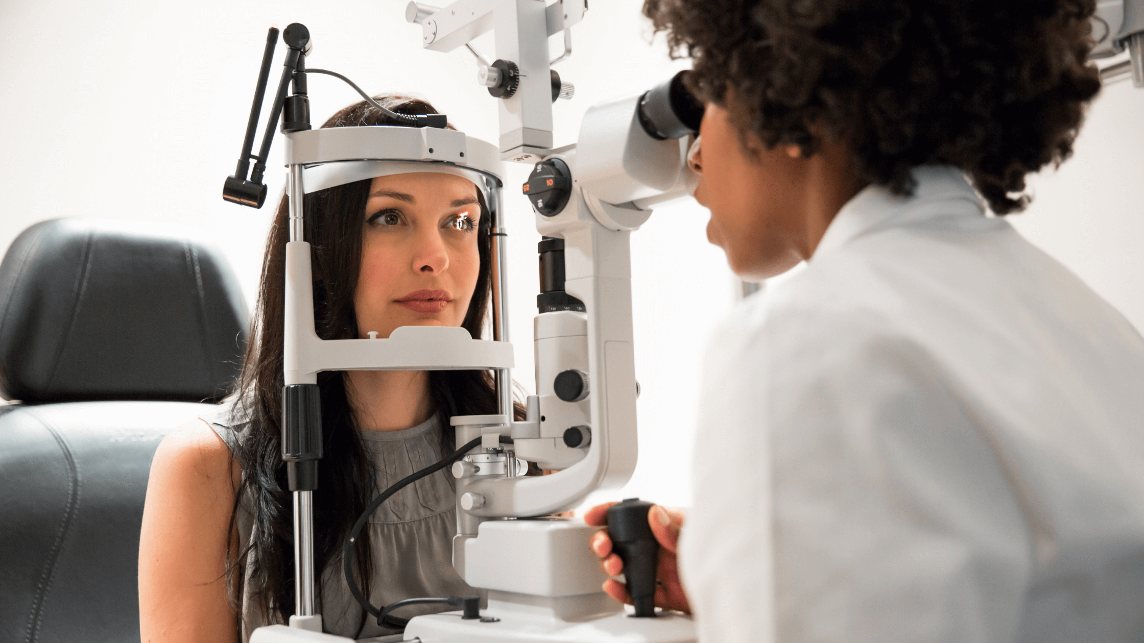 An ophthalmologist examining a patient's eyes with a slit lamp machine during a comprehensive eye exam to check for macular degeneration.