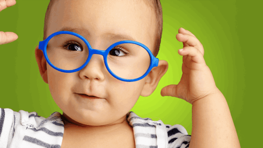 A close-up of a baby wearing large, round blue training glasses, symbolizing the need for early and regular child eye exams starting in infancy.